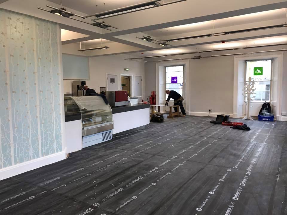 Interior of canteen under renovation with workman and equipment.