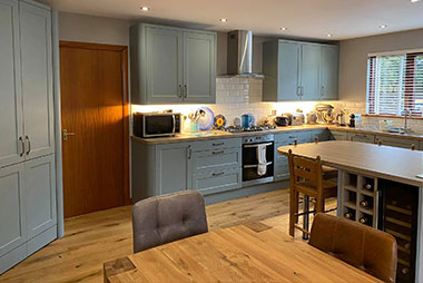 Modern kitchen with wooden floors and grey cabinets.