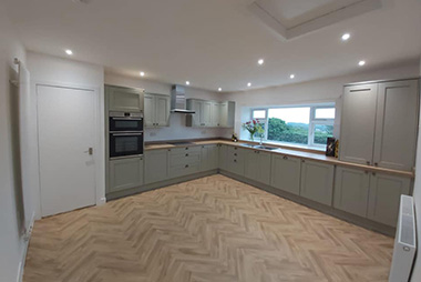 Modern kitchen with herringbone floor and grey cabinets.