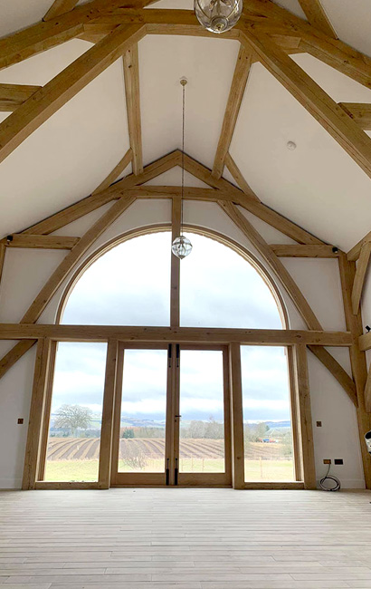 Spacious barn conversion with large arched window and beams.
